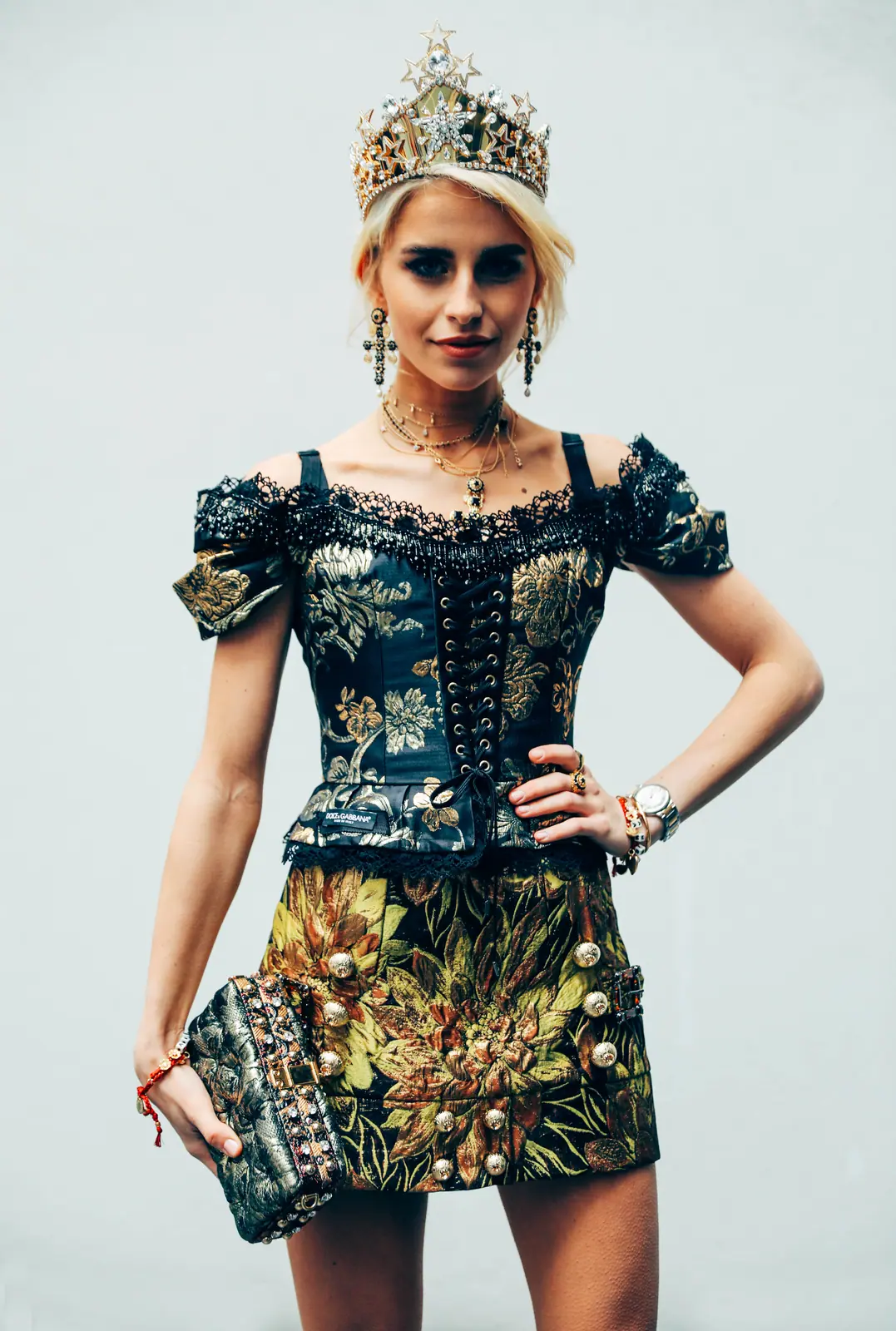 Caro Daur: model in a jewelled crown and brocade dress, hand on hip